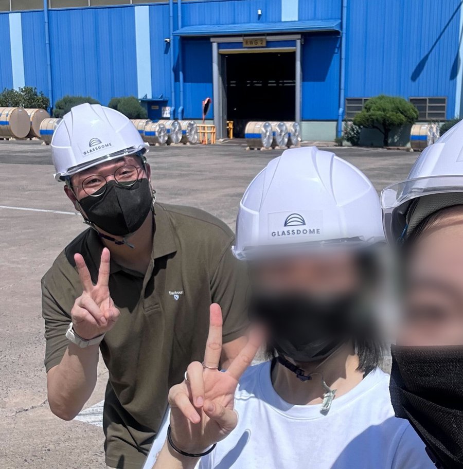 The team on-site at a running factory in GLASSDOME hard hats during field research, teammates' faces blurred